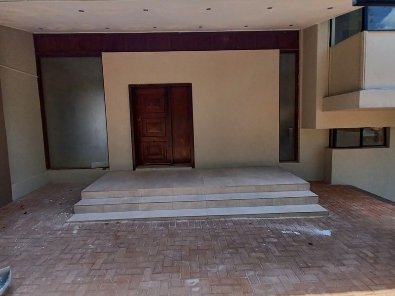 Front entrance featuring a timber door, tiled steps, and paved driveway area with recessed ceiling lighting.