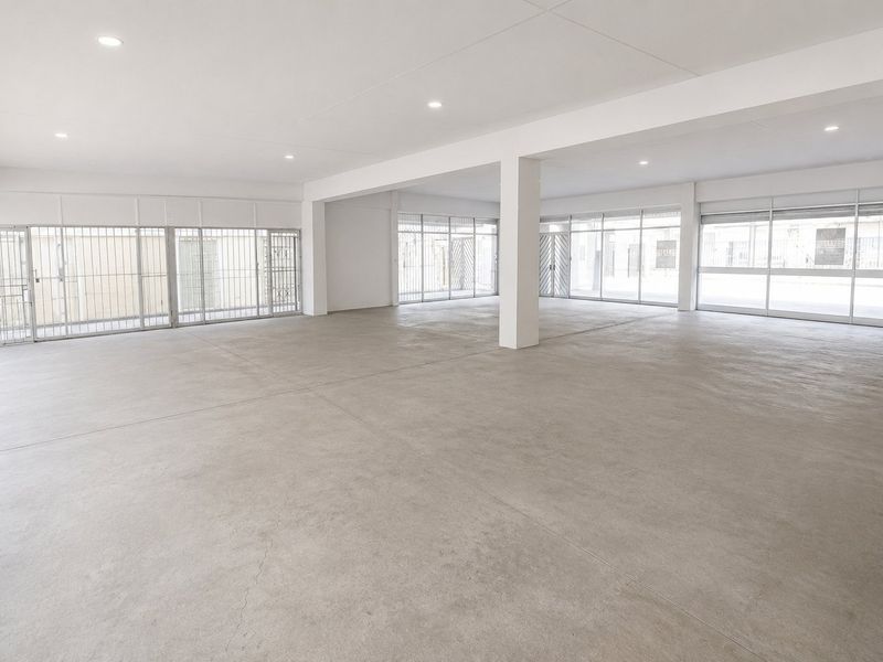 Spacious open-plan commercial unit featuring polished concrete floors, recessed lighting, and extensive glass frontage with integrated security gates.
