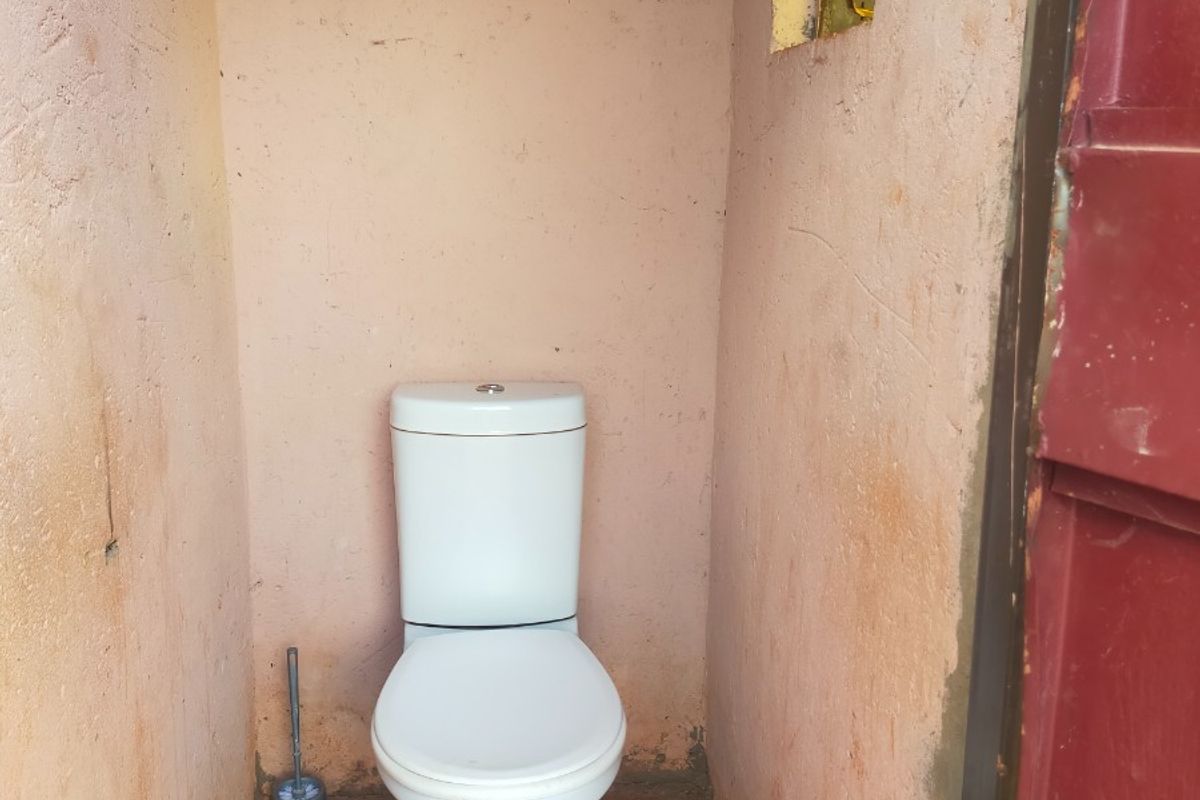 A small, basic bathroom facility featuring a standard toilet, requiring significant cosmetic updates and wall finishing to improve the overall condition.