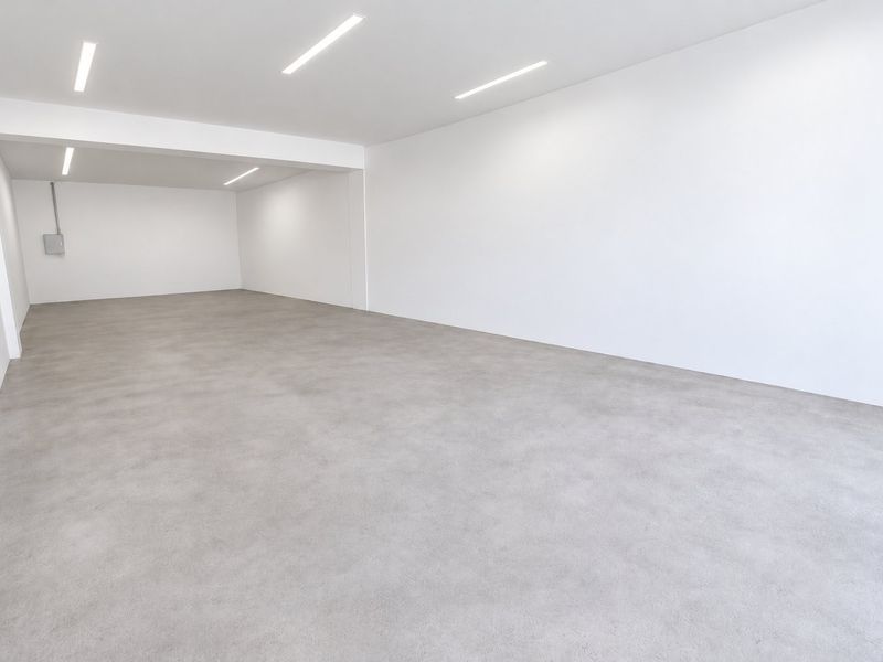 A spacious, minimalist open-plan commercial area featuring polished concrete flooring and modern recessed linear lighting, offering a clean and versatile blank canvas.