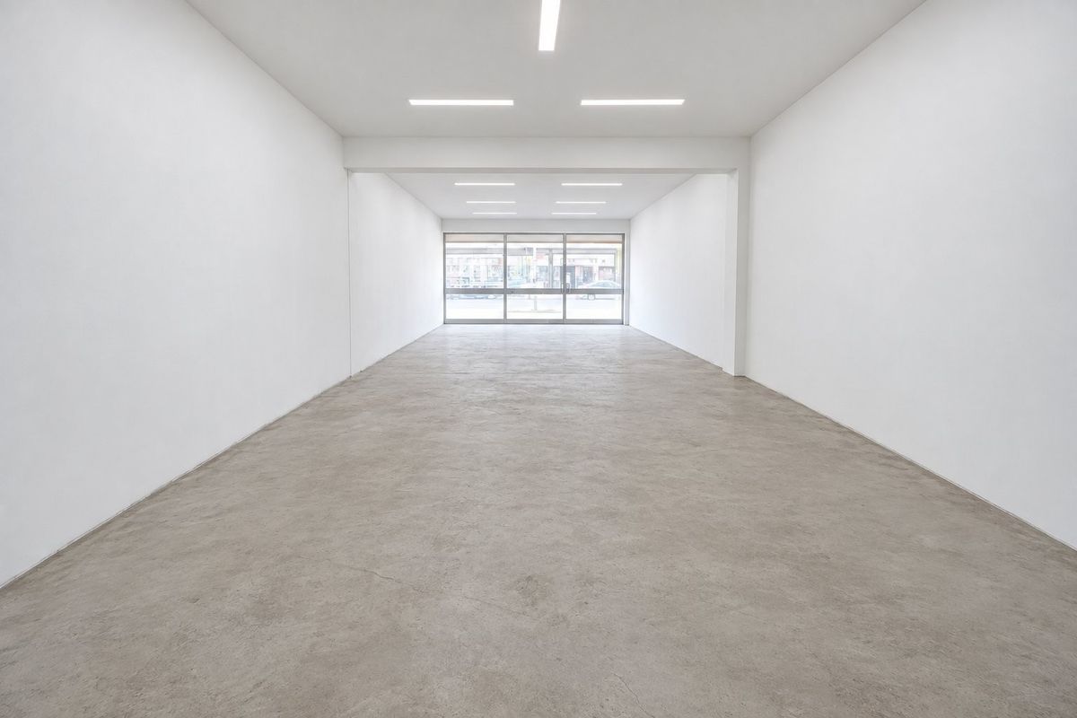 A bright, open-plan commercial space featuring polished concrete floors, recessed lighting, and a large glass storefront entrance, ideal for retail or office use.