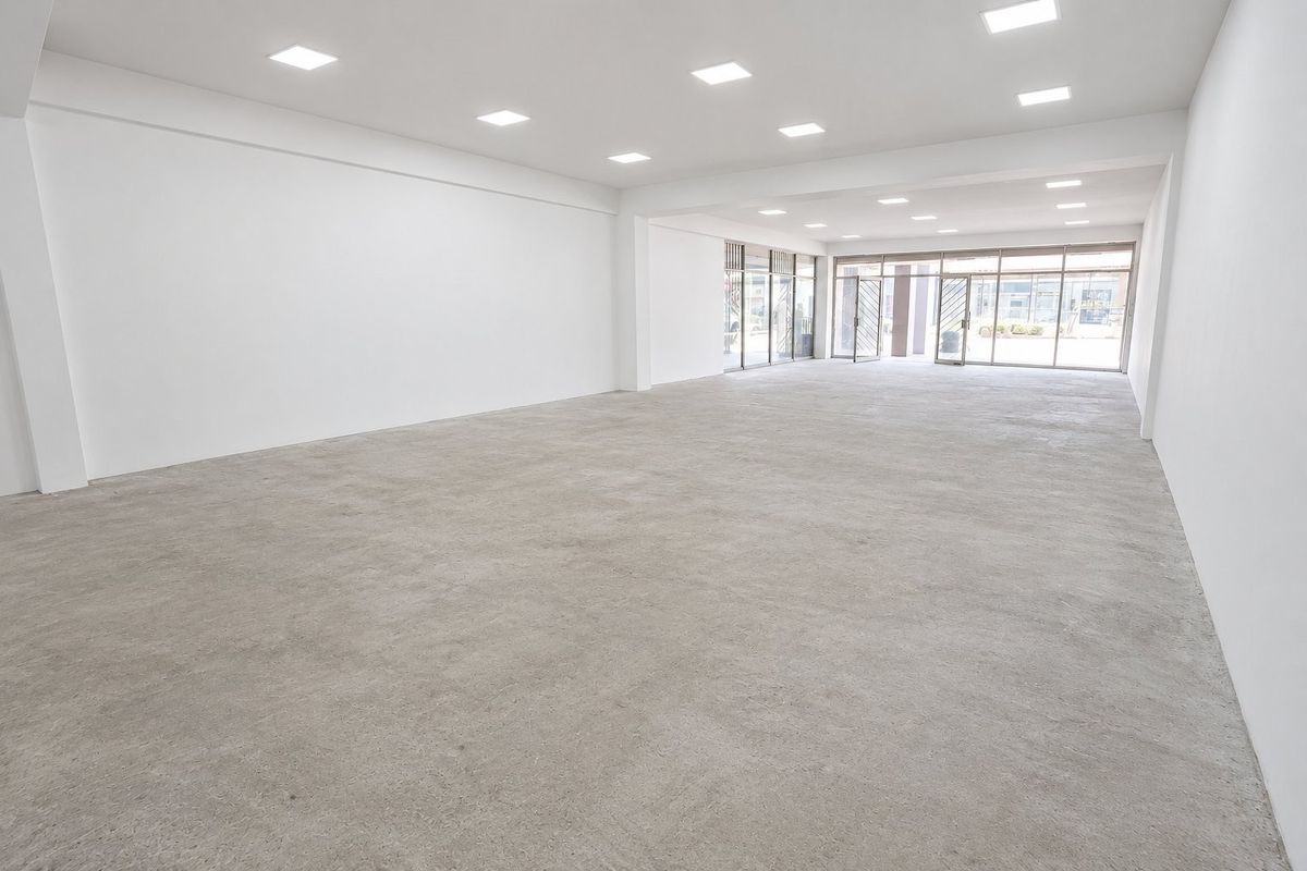 A spacious, open-plan commercial unit featuring polished concrete floors, recessed ceiling lighting, and large glass storefront windows providing ample natural light.