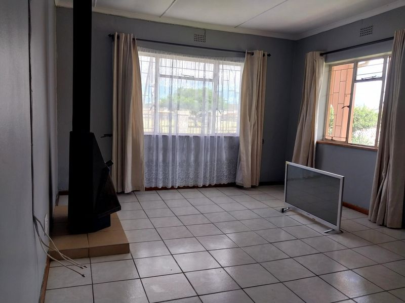 Spacious living room featuring tiled flooring and a freestanding fireplace, offering a bright and neutral space ready for personalization.