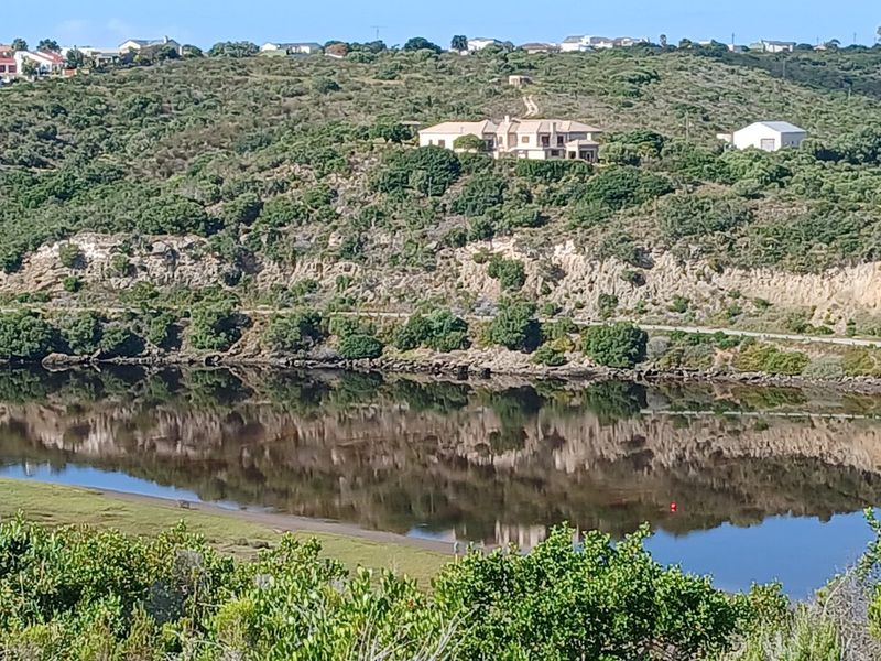 A scenic view of a tranquil water body reflecting the surrounding rocky landscape and natural vegetation.