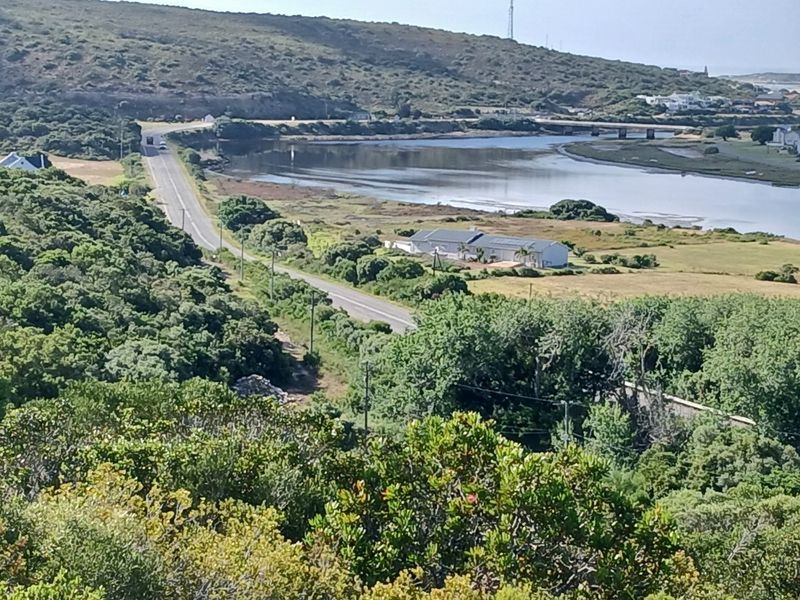 An elevated aerial view of the surrounding landscape, featuring a road, natural vegetation, and a nearby waterway.