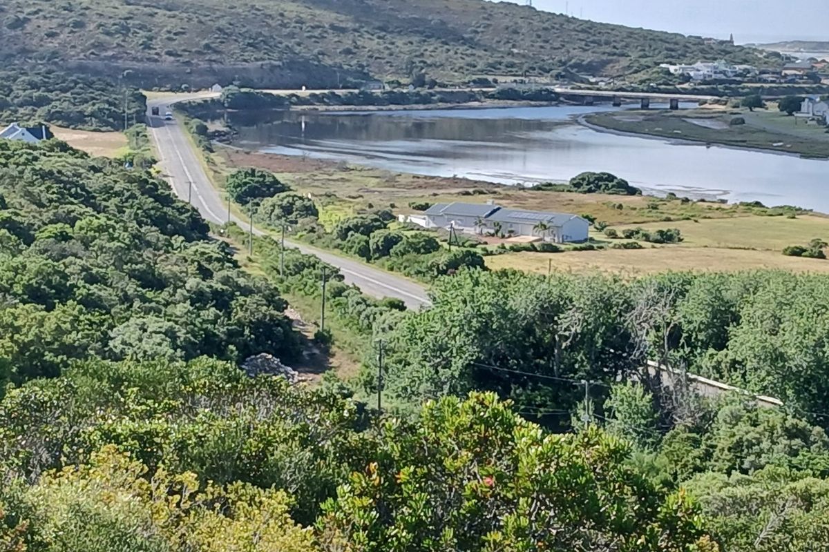An elevated aerial view of the surrounding landscape, featuring a road, natural vegetation, and a nearby waterway.