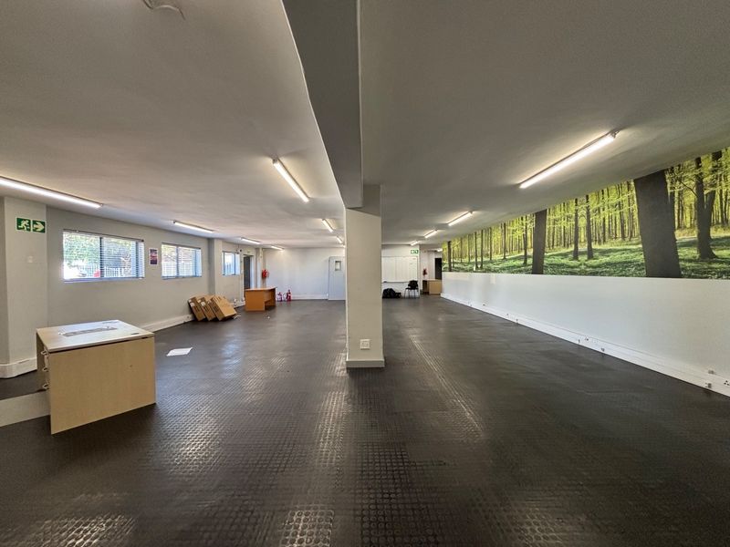 Spacious open-plan office area featuring durable rubber flooring, central support column, and bright fluorescent lighting, suitable for a flexible workspace layout.