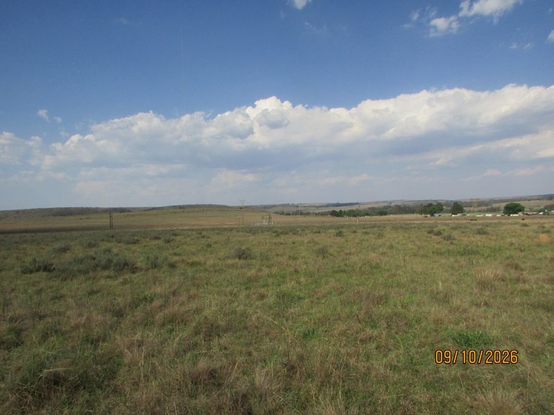 A wide-angle view of the expansive open grassland and rolling hills characteristic of the farm property.