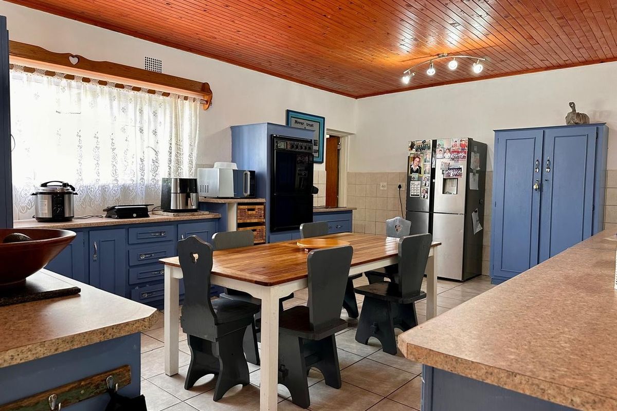 Spacious kitchen featuring timber ceiling, tiled flooring, built-in cabinetry, and integrated oven, offering a functional layout with ample space for a dining area.