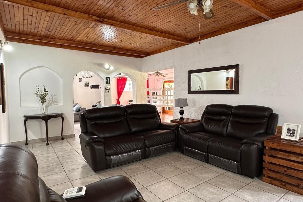 Spacious living room featuring a distinctive timber-clad ceiling, tiled flooring, and elegant arched doorways leading to adjacent living areas.