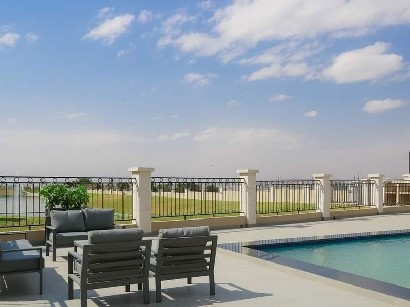 A well-maintained outdoor pool area featuring a paved deck, secure wrought iron fencing with masonry pillars, and clear views of the surrounding landscape.