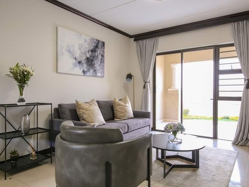 A well-maintained living room featuring tiled flooring, crown molding, and a sliding glass door providing access to an outdoor patio area.