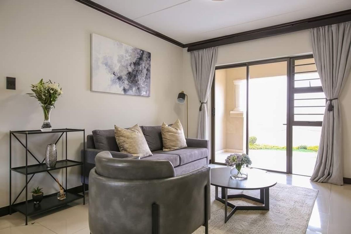 A well-maintained living room featuring tiled flooring, crown molding, and a sliding glass door providing access to an outdoor patio area.