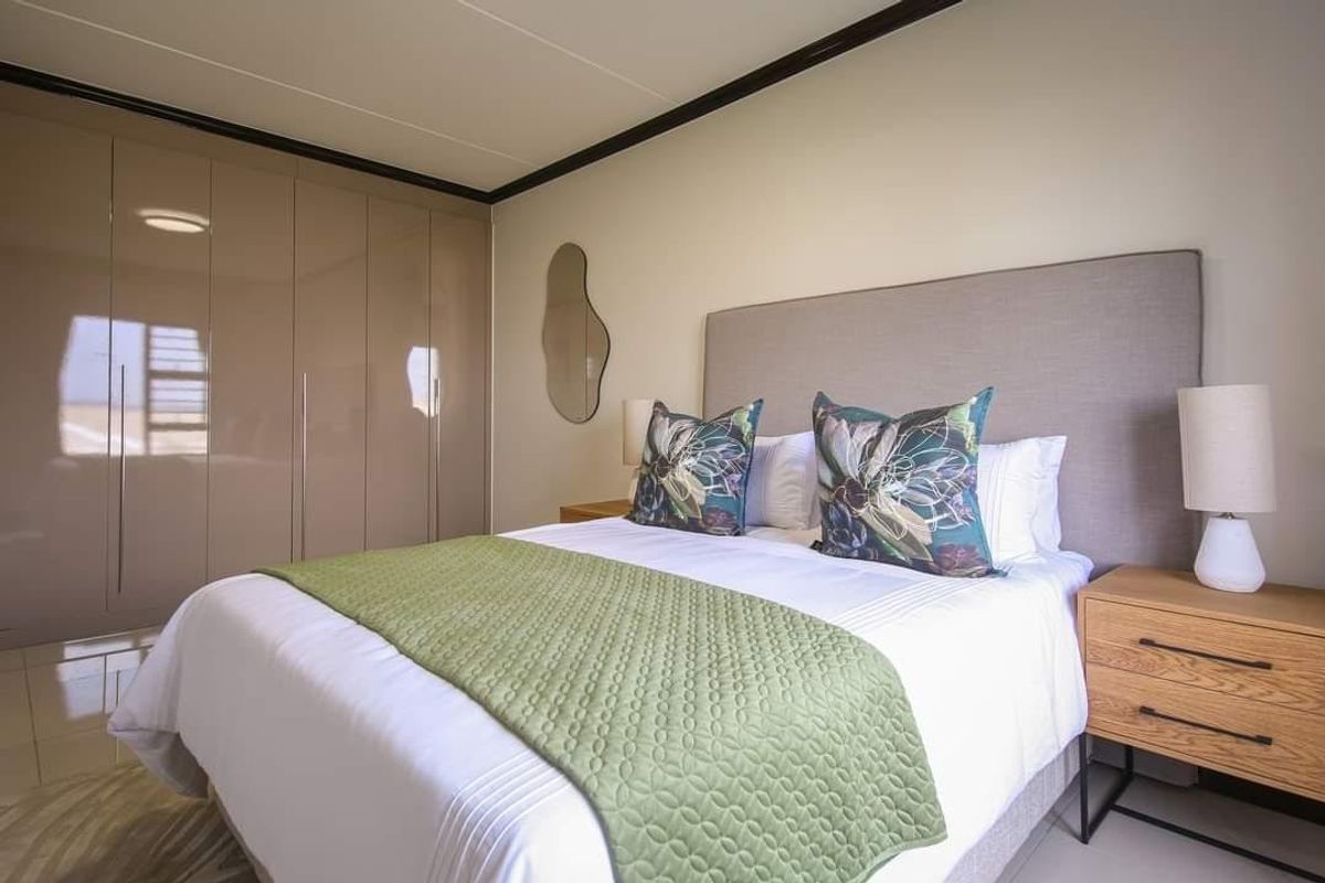 A well-maintained bedroom featuring sleek built-in cupboards, neutral wall finishes, and modern tiled flooring.