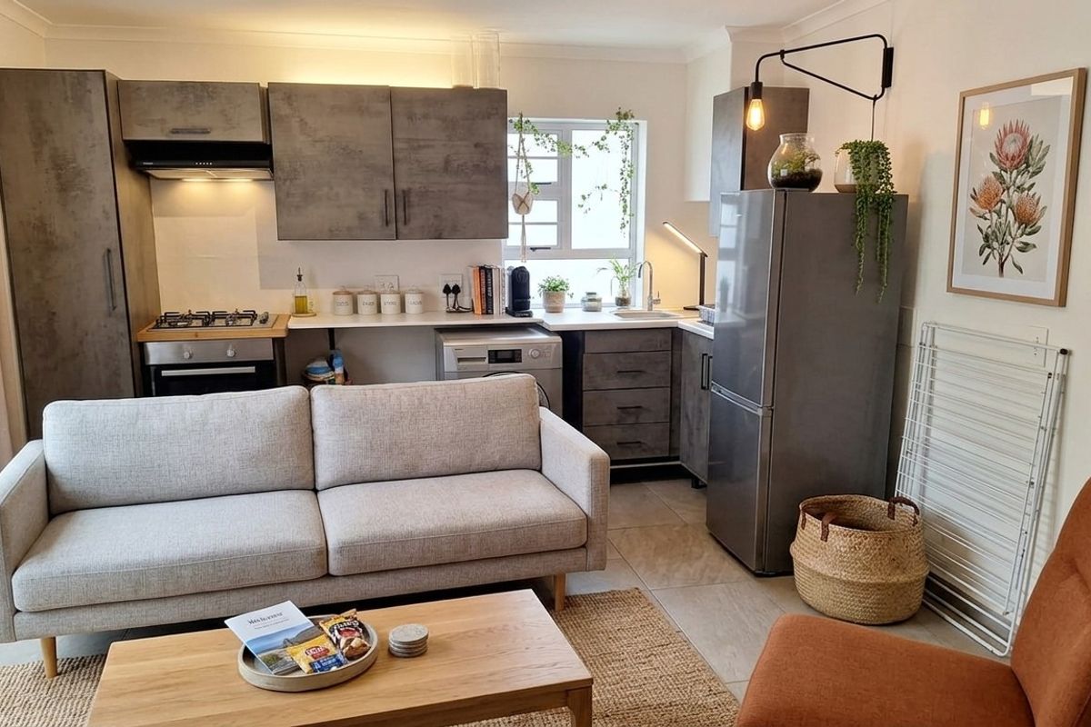 A modern open-plan living and kitchen area featuring contemporary grey cabinetry, integrated appliances, tiled flooring, and a functional layout.