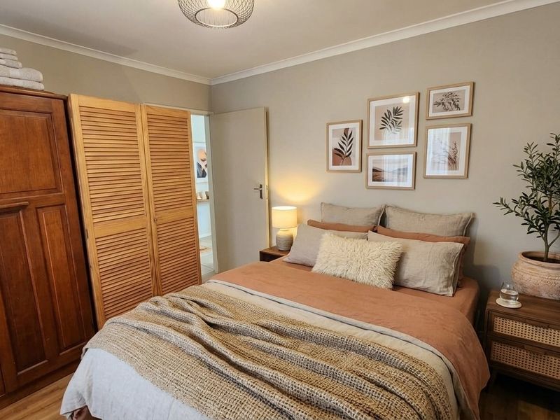 A well-presented bedroom featuring built-in wardrobes with louvered doors, neutral wall tones, and durable laminate flooring.