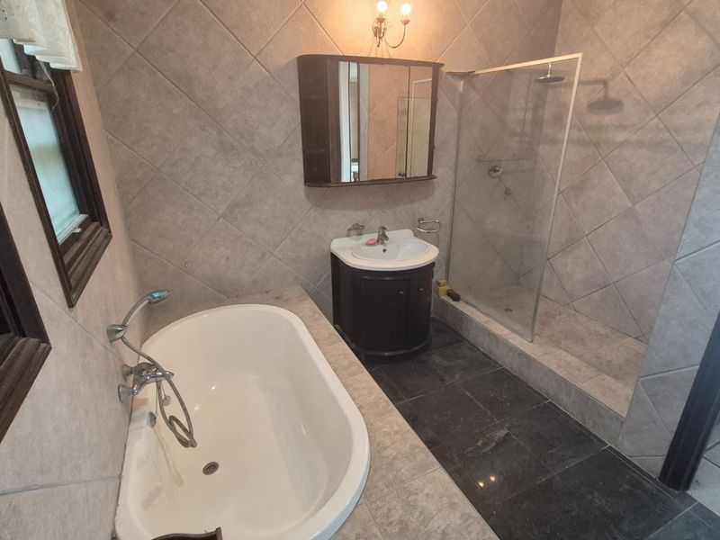 A well-appointed bathroom featuring a freestanding bathtub, a separate walk-in shower with a glass screen, and a vanity cabinet with a mirror.