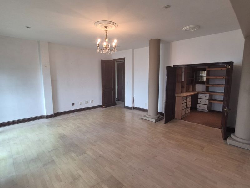 Spacious living area featuring parquet flooring, decorative ceiling details, structural columns, and a convenient built-in study nook.