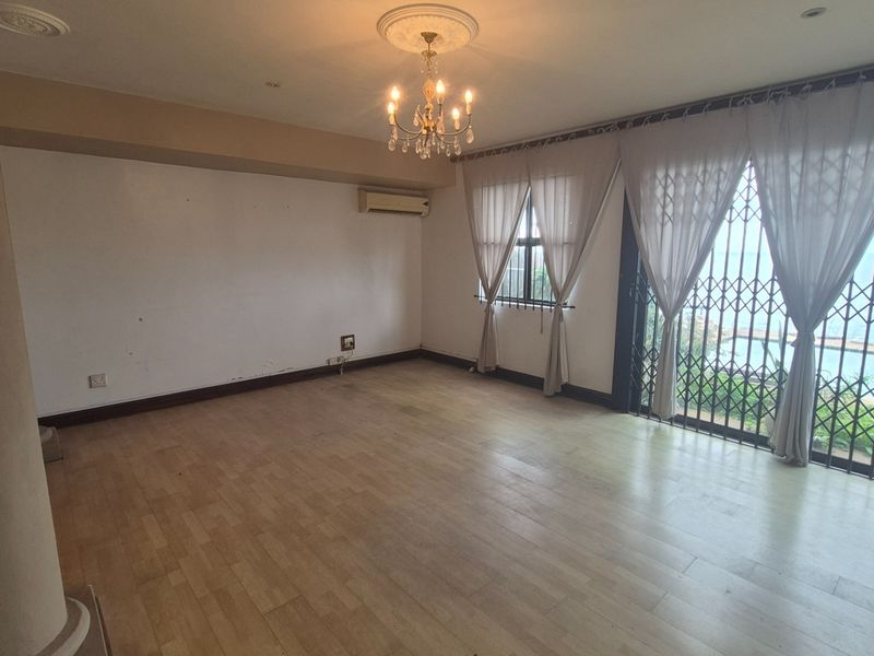 Spacious living area featuring laminate flooring, a decorative chandelier, and large sliding doors leading to an outdoor view with security gates.