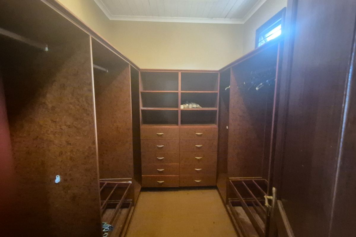 A walk-in closet featuring extensive built-in wooden cabinetry, drawers, and hanging rails, providing ample storage space.