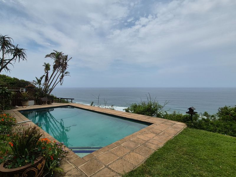 Outdoor swimming pool area featuring a paved surround and expansive ocean views, set within a landscaped garden environment.