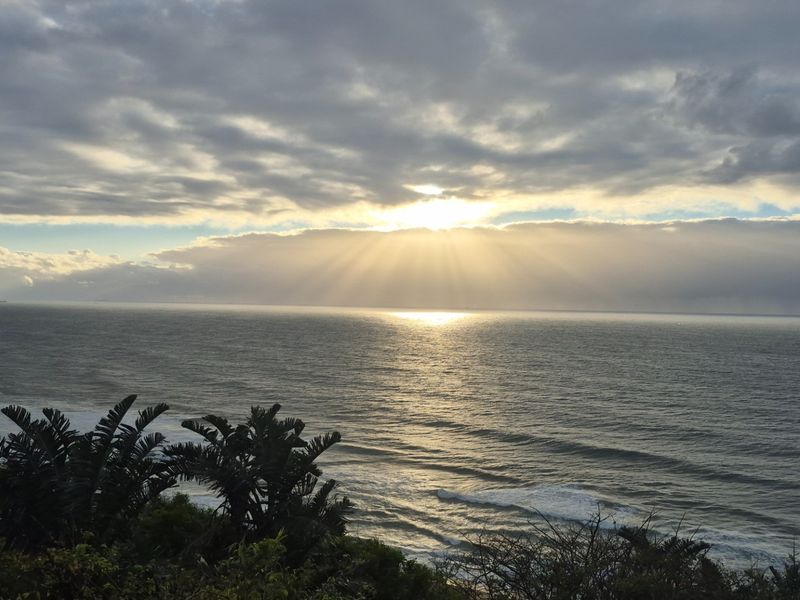 A scenic ocean view featuring a dramatic sunset over the horizon, showcasing the natural coastal landscape.