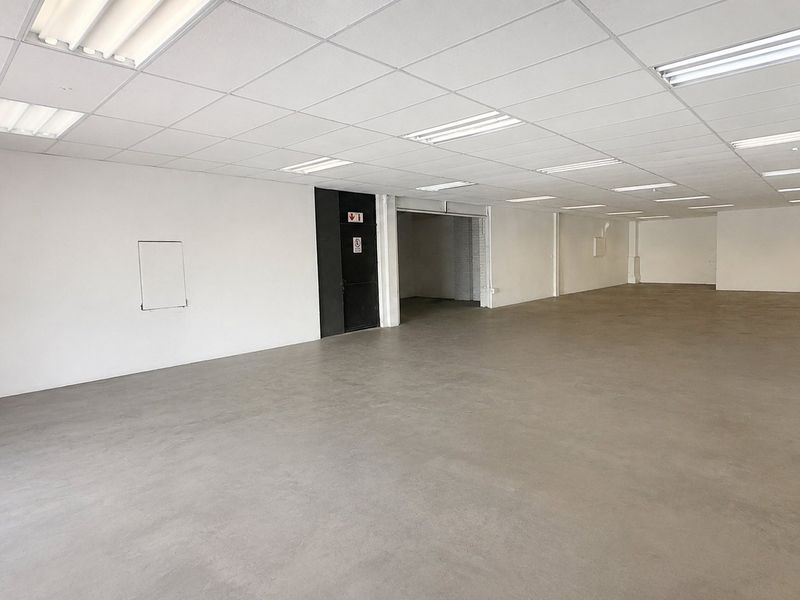 A spacious, open-plan commercial unit featuring a clean concrete floor, suspended ceiling with integrated lighting, and neutral white walls, ready for custom fit-out.