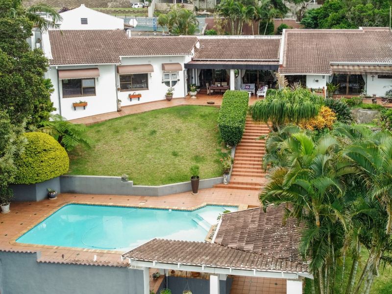 Aerial view of the rear property featuring a swimming pool, tiled patio, landscaped garden, and a spacious covered outdoor entertainment area.