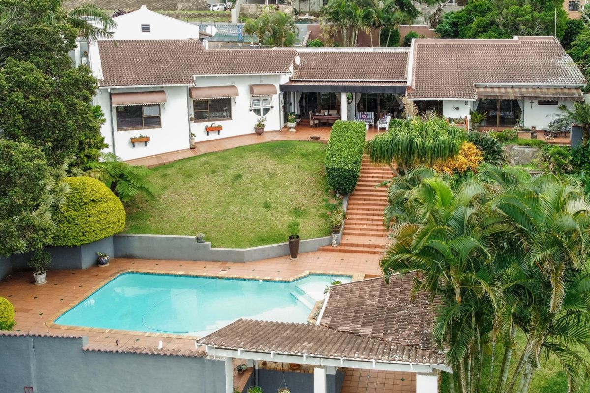 Aerial view of the rear property featuring a swimming pool, tiled patio, landscaped garden, and a spacious covered outdoor entertainment area.