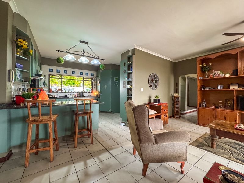 Open-plan living and kitchen area featuring tiled flooring, granite countertops, and built-in cabinetry, offering a functional and connected layout.