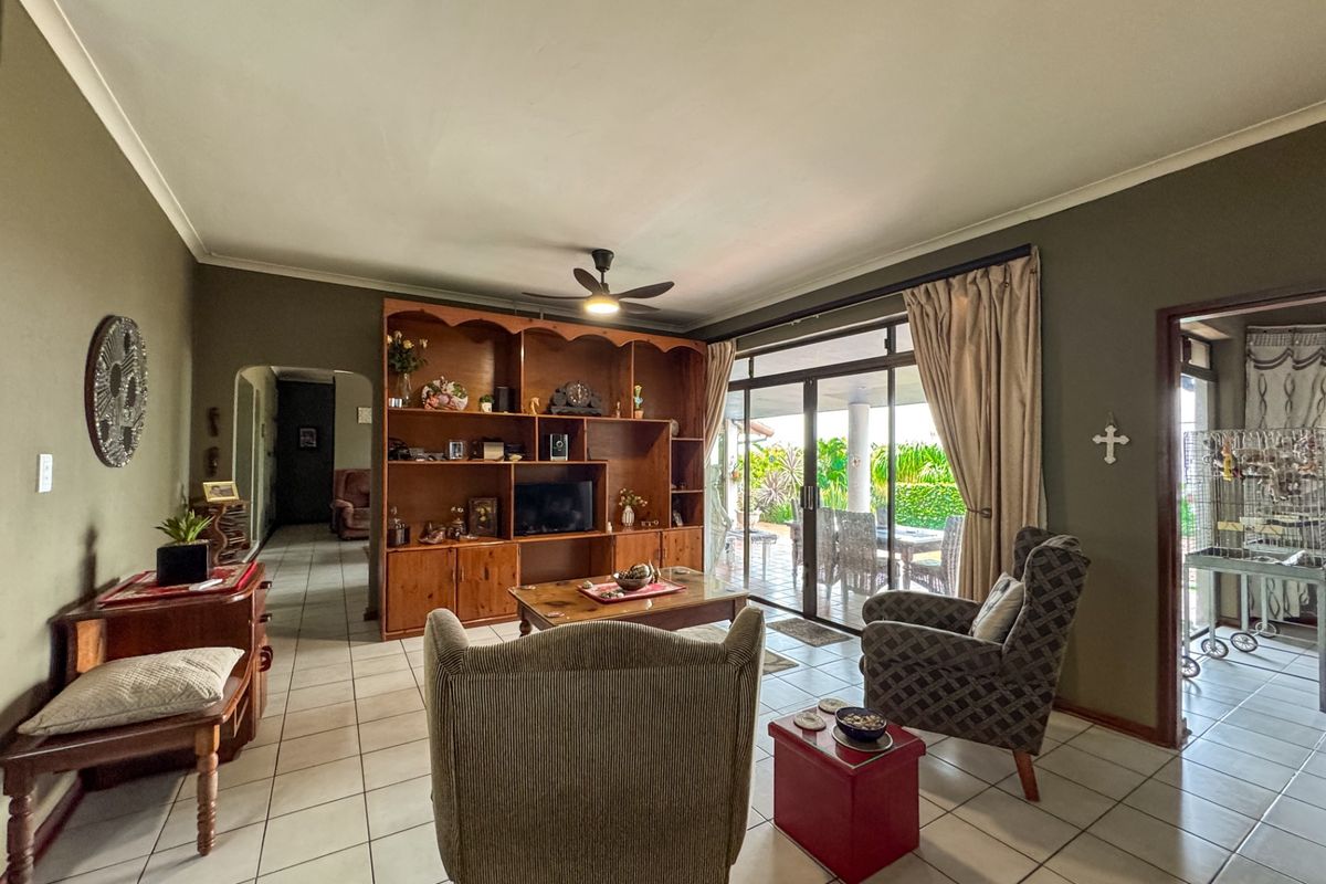 A spacious living room featuring tiled flooring, a large built-in wooden display unit, and sliding glass doors providing direct access to the patio.