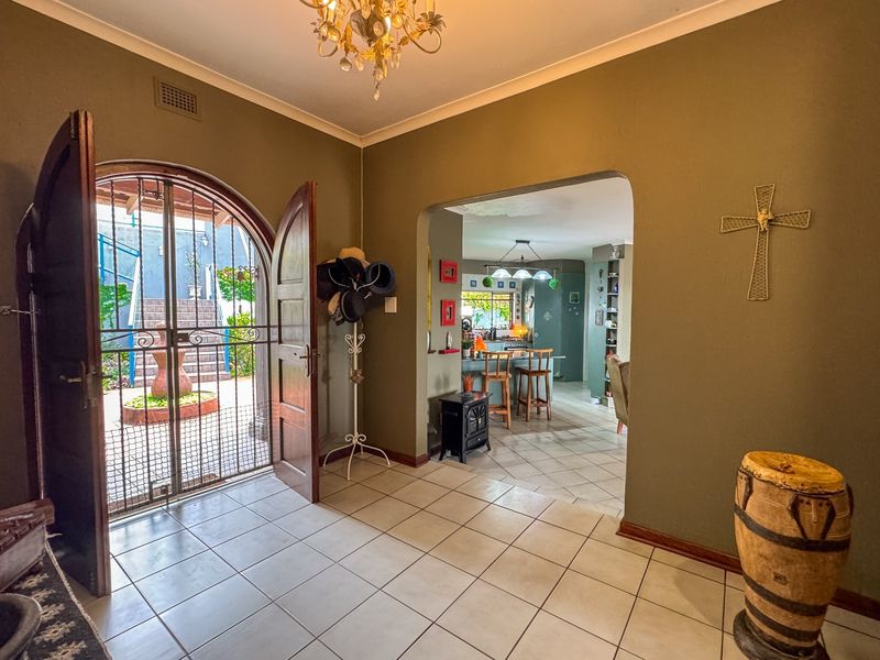 Welcoming entrance hall with ceramic tile flooring, arched doorway leading to the exterior, and an open-plan view into the kitchen area.