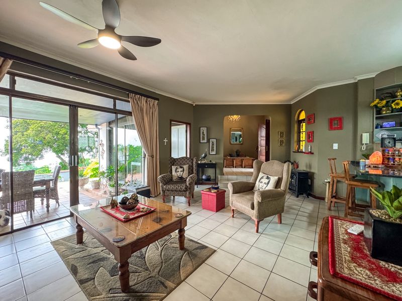 Spacious open-plan living area featuring tiled flooring, a ceiling fan, and large sliding glass doors providing seamless access to the outdoor patio.