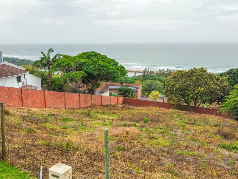 A vacant residential plot featuring a brick boundary wall and expansive ocean views, offering a prime location for future development.