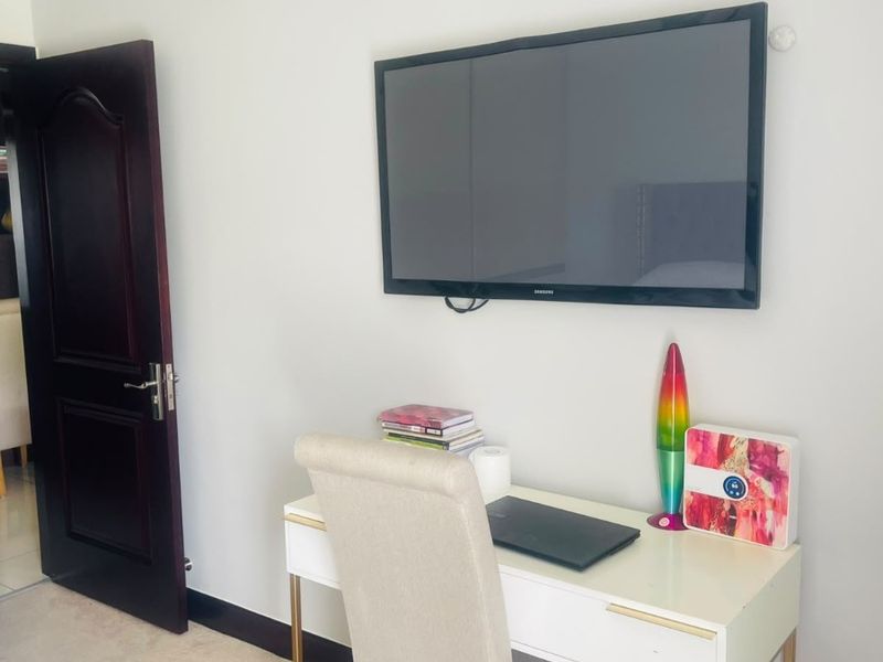 A bedroom interior featuring a dark wood door and neutral wall finishes, currently utilized as a workspace.