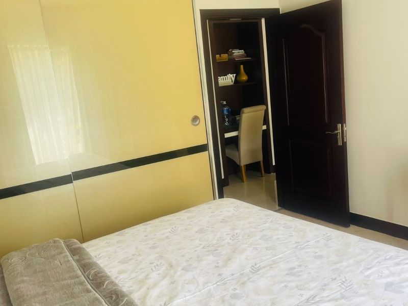 Bedroom featuring a large built-in wardrobe with sliding doors and a dark wood internal door leading to an adjacent study nook.