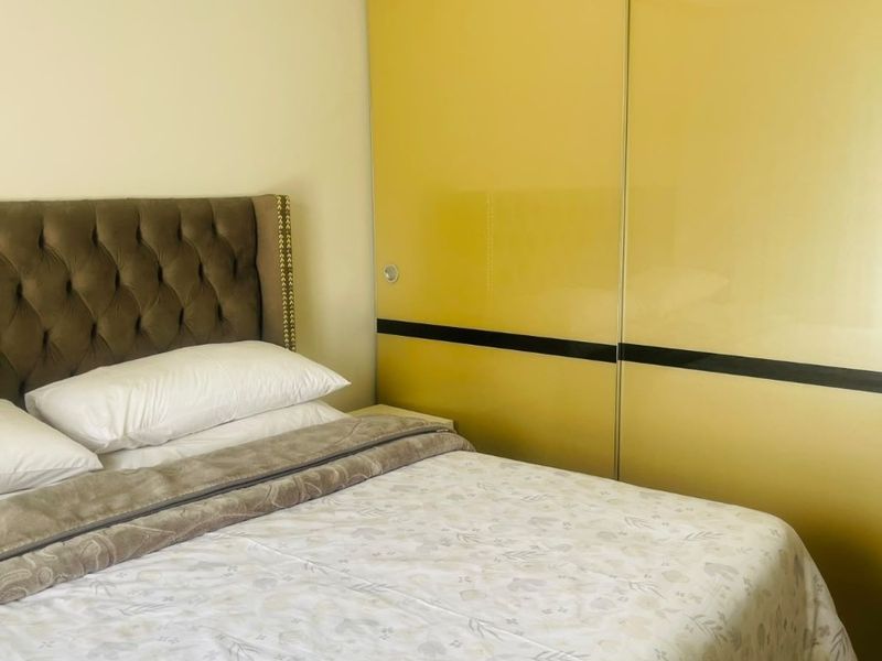 A bedroom featuring a large, yellow high-gloss built-in wardrobe with sliding doors, providing ample storage space.