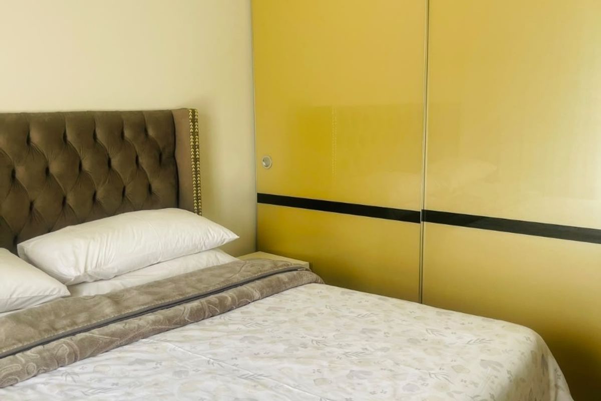 A bedroom featuring a large, yellow high-gloss built-in wardrobe with sliding doors, providing ample storage space.