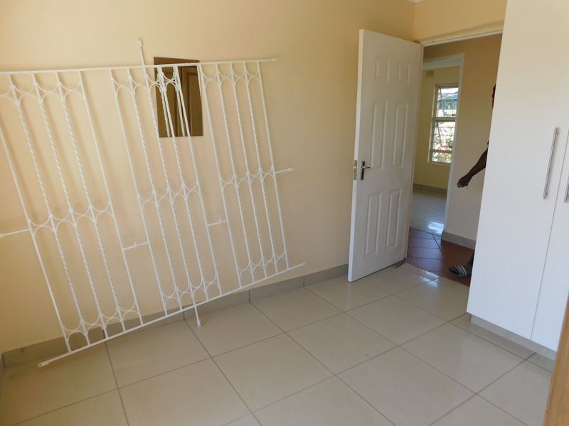 A clean, empty bedroom featuring neutral wall paint, tiled flooring, and built-in cupboards, offering a versatile space ready for personalization.