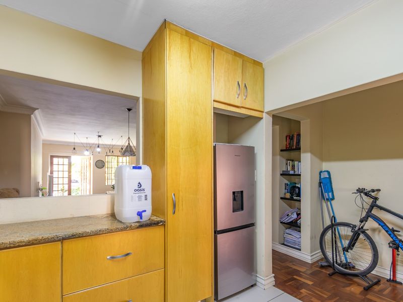 Kitchen area featuring light wood cabinetry, granite countertops, and built-in shelving, with an open-plan layout connecting to the adjacent living space.