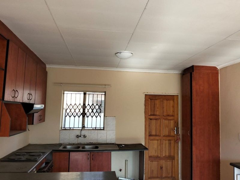 A dated kitchen featuring wooden cabinetry, a double sink, and built-in stove, offering a functional layout ready for modernization and cosmetic updates.