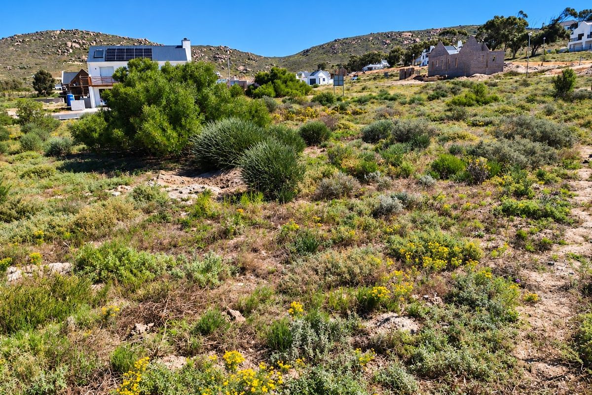 A view of a vacant residential plot featuring natural vegetation and surrounding hillside landscape in a quiet coastal estate.