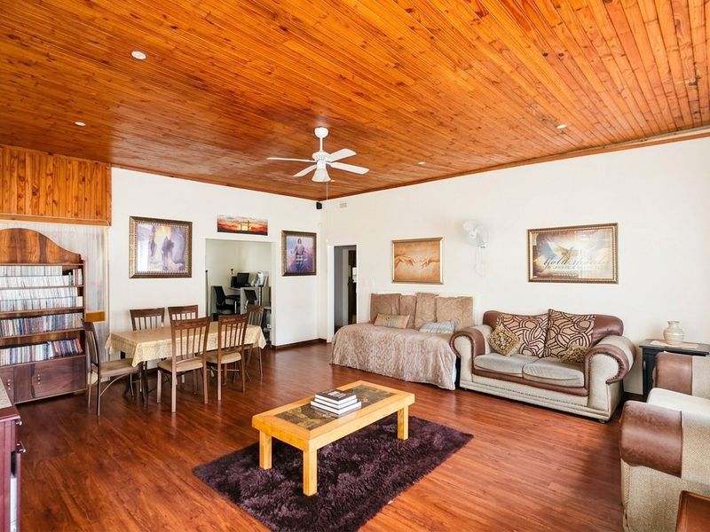 Spacious open-plan living and dining area featuring warm timber tongue and groove ceilings and durable laminate flooring throughout.