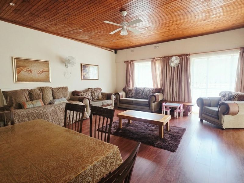 Spacious living area featuring a warm timber-clad ceiling, ceiling fan, and laminate flooring with direct access to the outdoors through sliding glass doors.