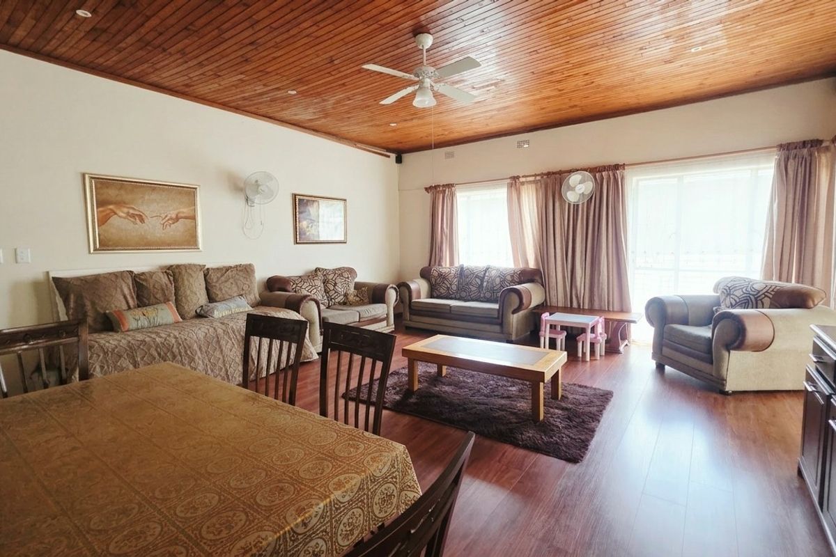 Spacious living area featuring a warm timber-clad ceiling, ceiling fan, and laminate flooring with direct access to the outdoors through sliding glass doors.