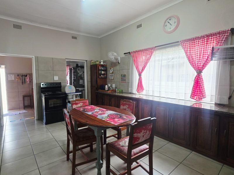 A functional kitchen featuring built-in wooden cabinetry, granite countertops, tiled flooring, and a freestanding stove, with a dedicated dining area.