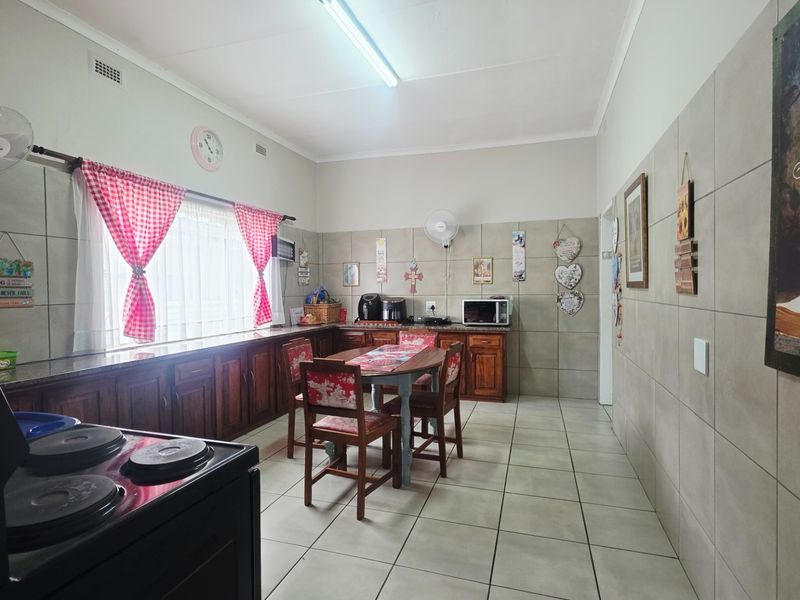 A functional kitchen featuring extensive wooden cabinetry, granite countertops, and neutral wall and floor tiling, offering a practical layout for daily use.