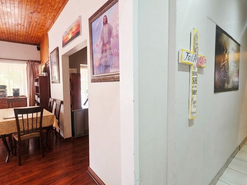 Open plan living and dining area featuring a timber ceiling, laminate flooring, and a transition to a tiled hallway.