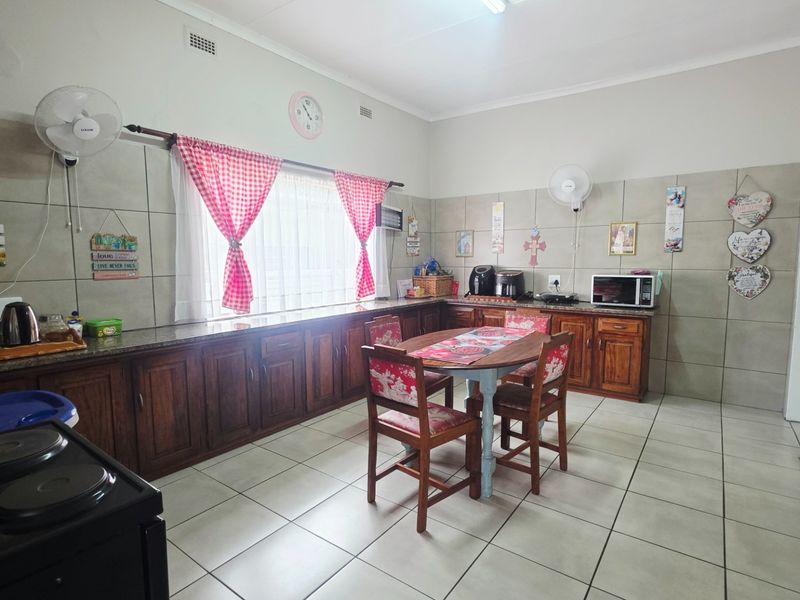 Spacious kitchen featuring extensive wooden cabinetry, granite countertops, and neutral tiled flooring with a dedicated dining area.