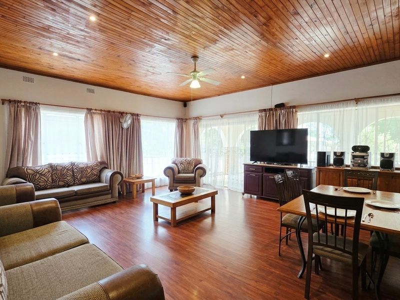 Spacious open-plan living and dining area featuring warm timber ceilings and laminate flooring, creating a comfortable and inviting atmosphere.